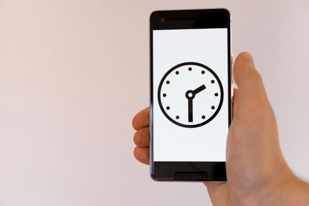 A person holding a smartphone with a clock image in it.