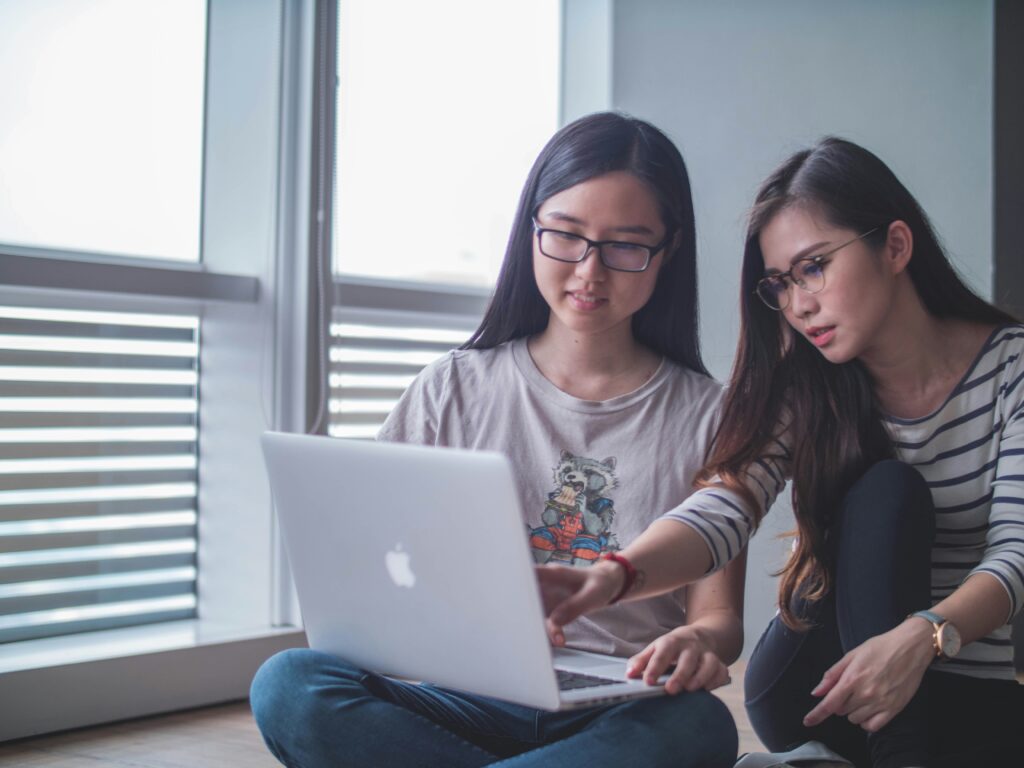 Two women discussing while looking at a laptop.