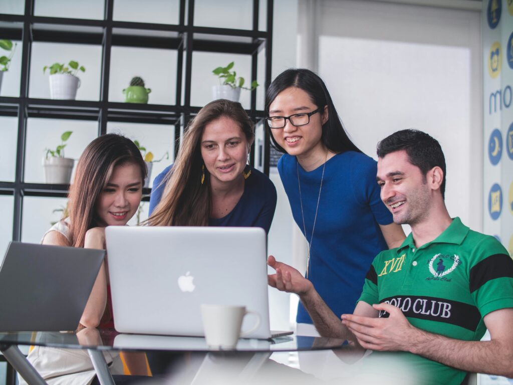 Four people looking at a MacBook.