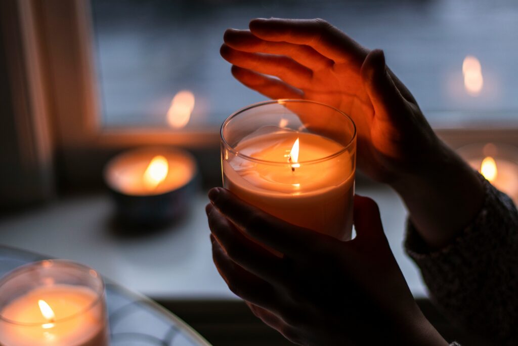 Picture of a person holding a lighted scented candle.