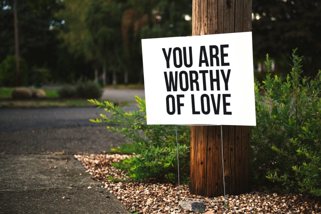 A white sign that reads “You are worthy of love.”