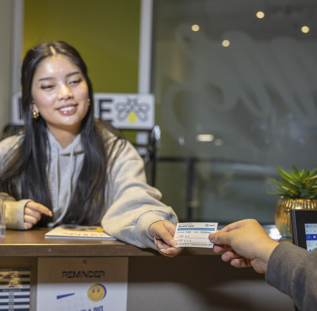 A student grabbing an IGNITE Health & Dental Insurance card.