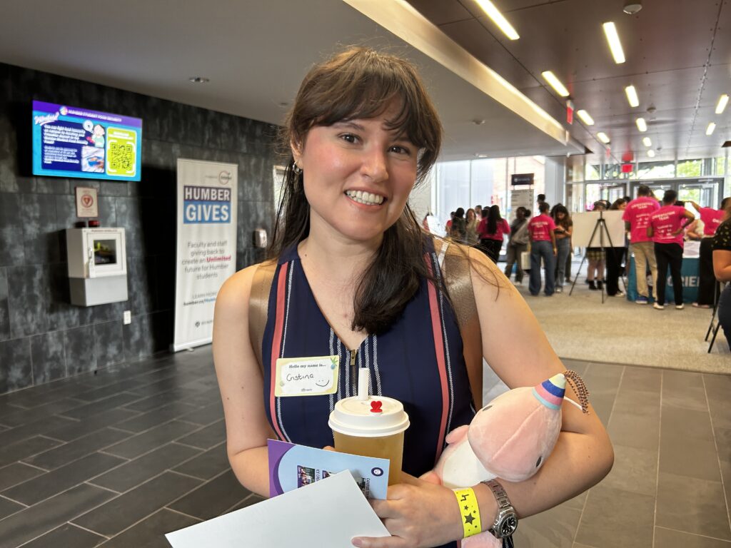 Humber student Cristina Valencia smiles as she holds a bubble tea and a plushie with both hands.