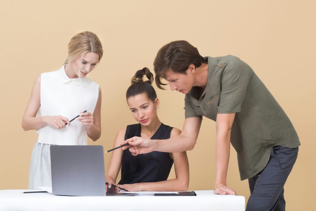 Three people analyzing and looking at a laptop.