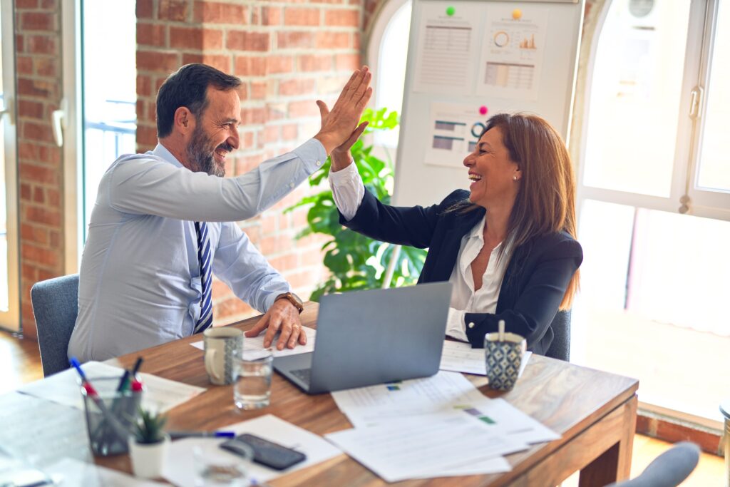 A man and a woman high-fiving each other in office. 