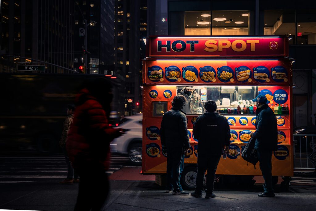 Three people standing in front of a food truck at night.