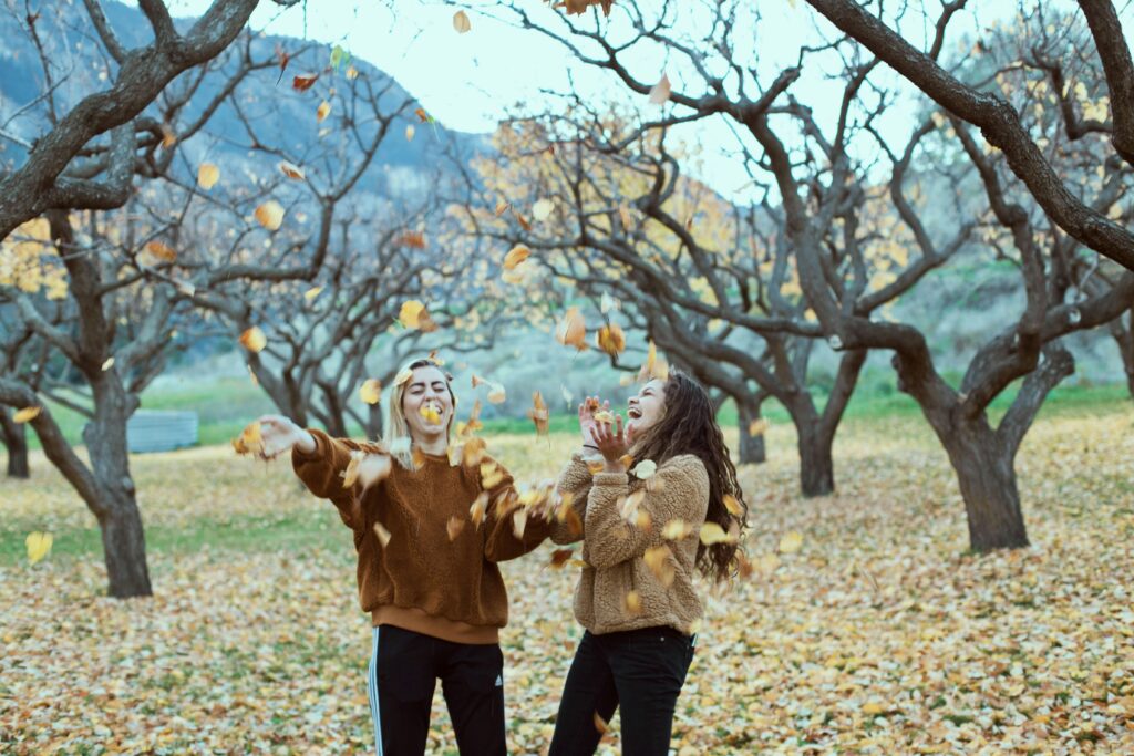 Two girls having fun with fall foliage