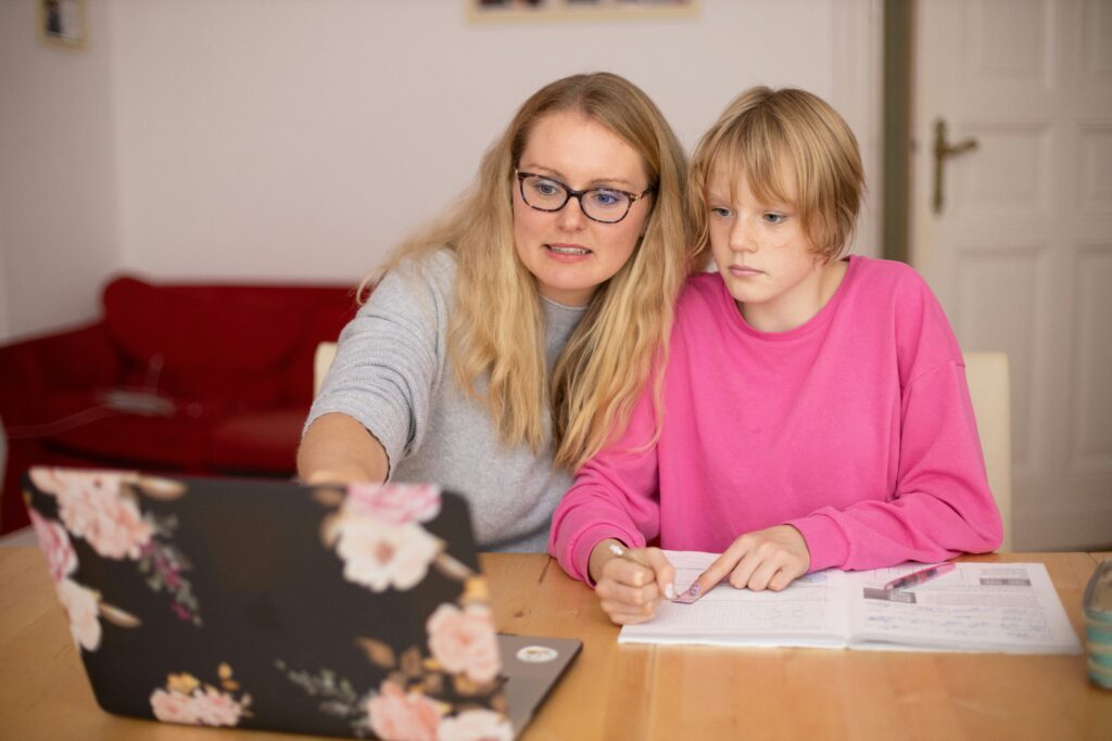 A woman is helping a girl with studies. 