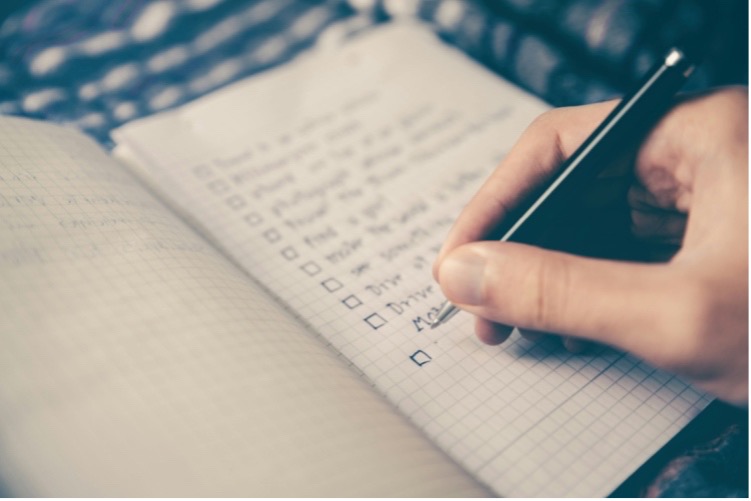 A person writing a to-do list in a notebook.