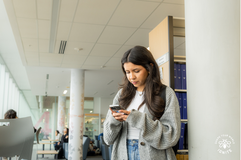 A student checking their phone at the library