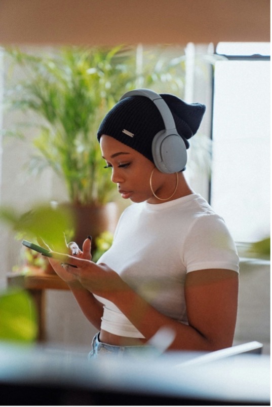 Woman using headphones and checking her phone.