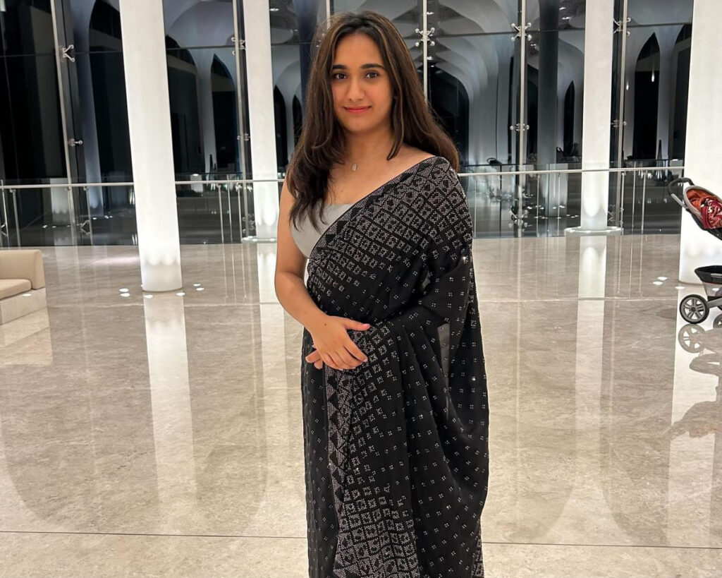 A woman in saree is standing in a hall. 