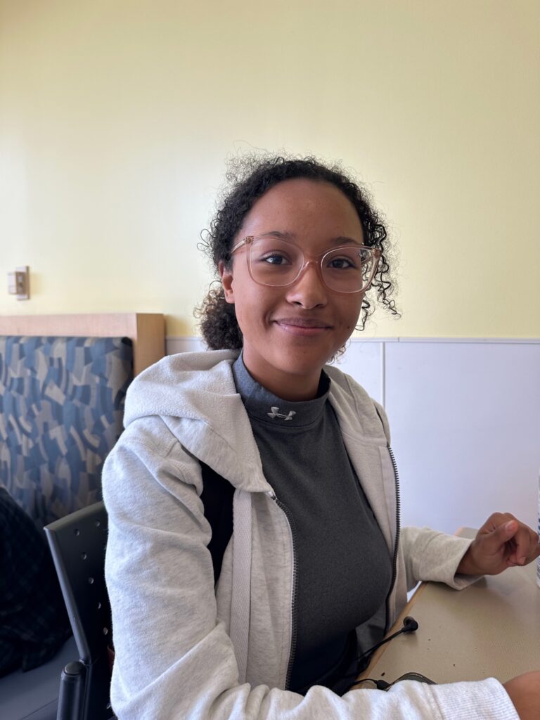 Headshot of student Miranda She sitting at a table located in the Lakeshore campus cafeteria.