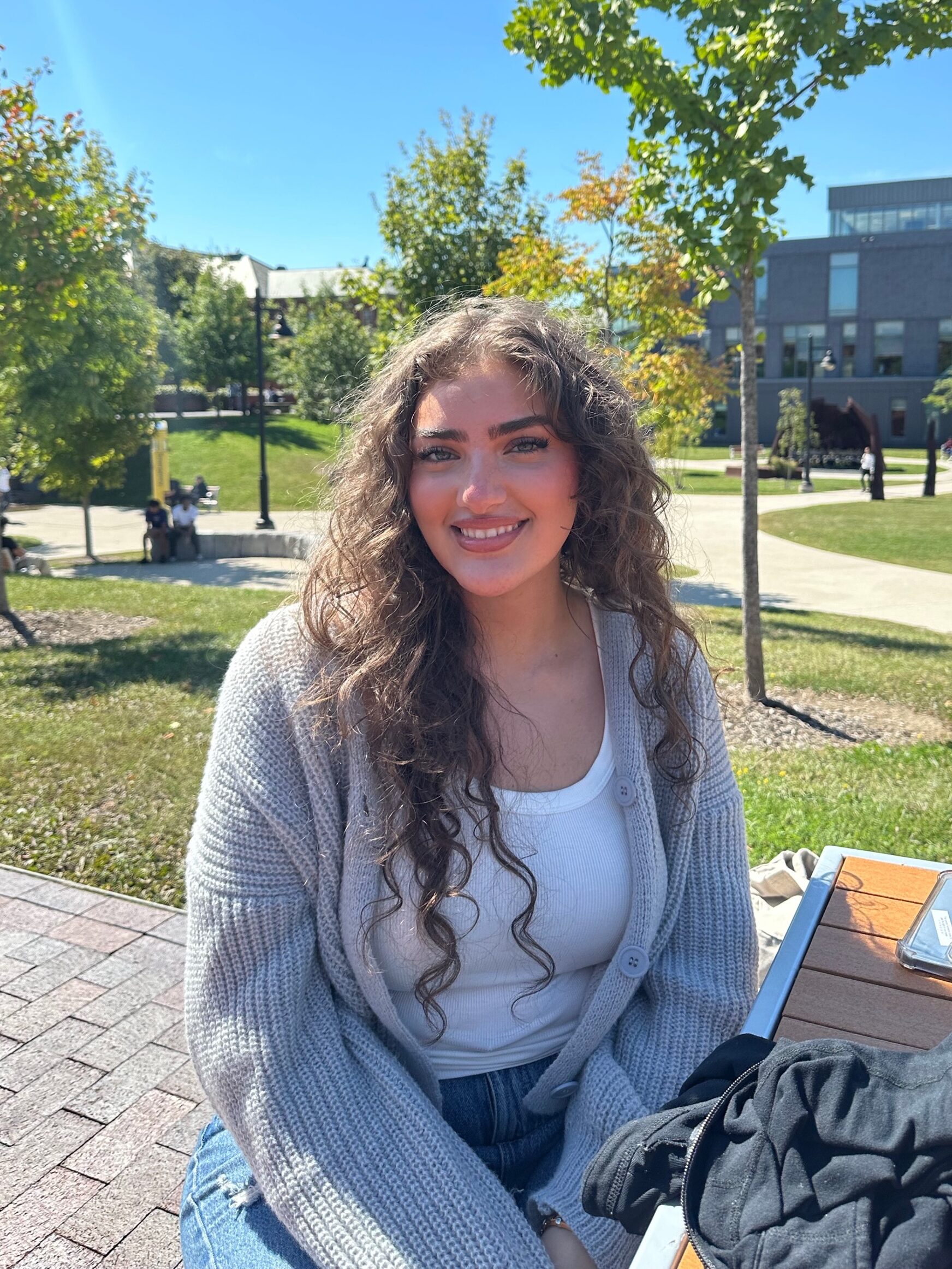 Headshot of student Rania Alattar sitting on an outside bench located on the Lakeshore campus.