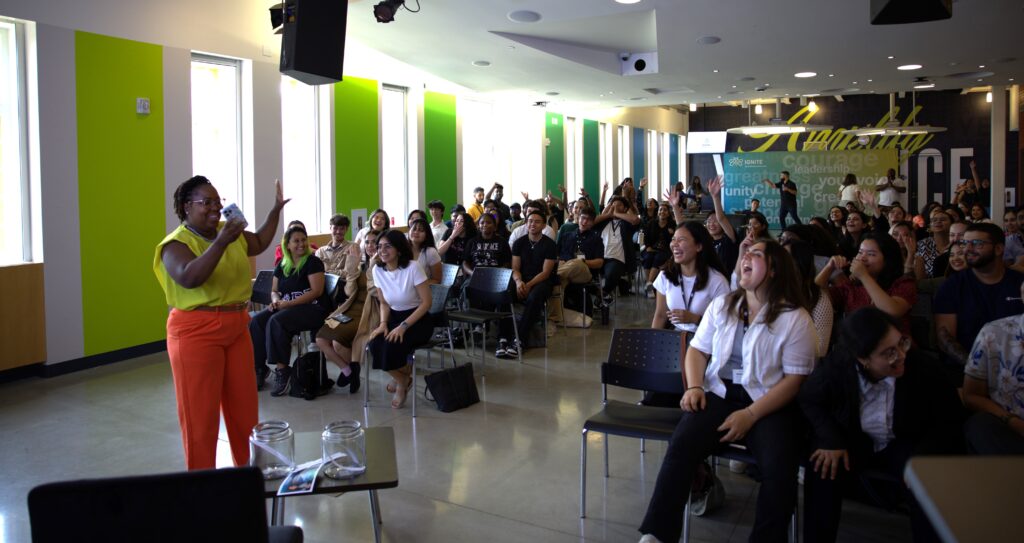 A big group of students are sitting together in a hall. 