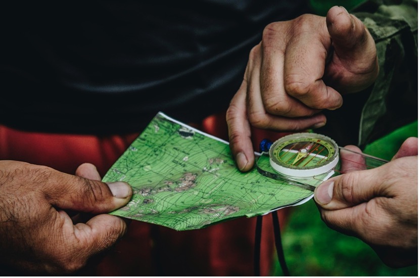 Two people holding map and clear compass. camping