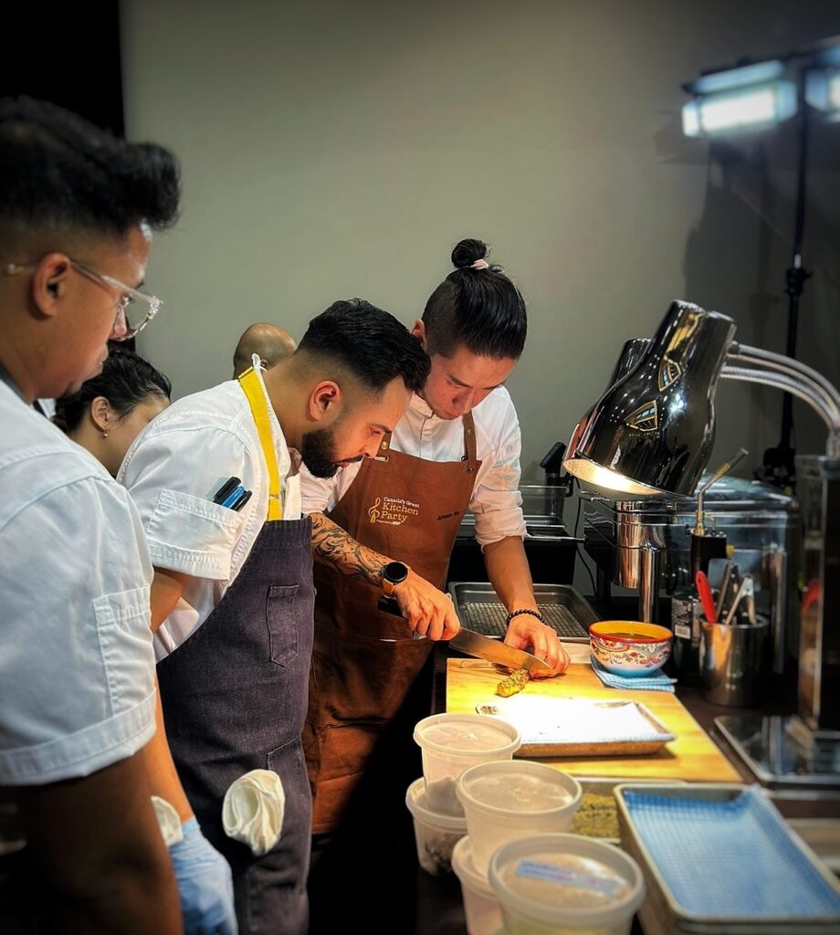 Chef Johnson Wu demonstrates the proper way to cut a sushi as his fellow chefs watch.