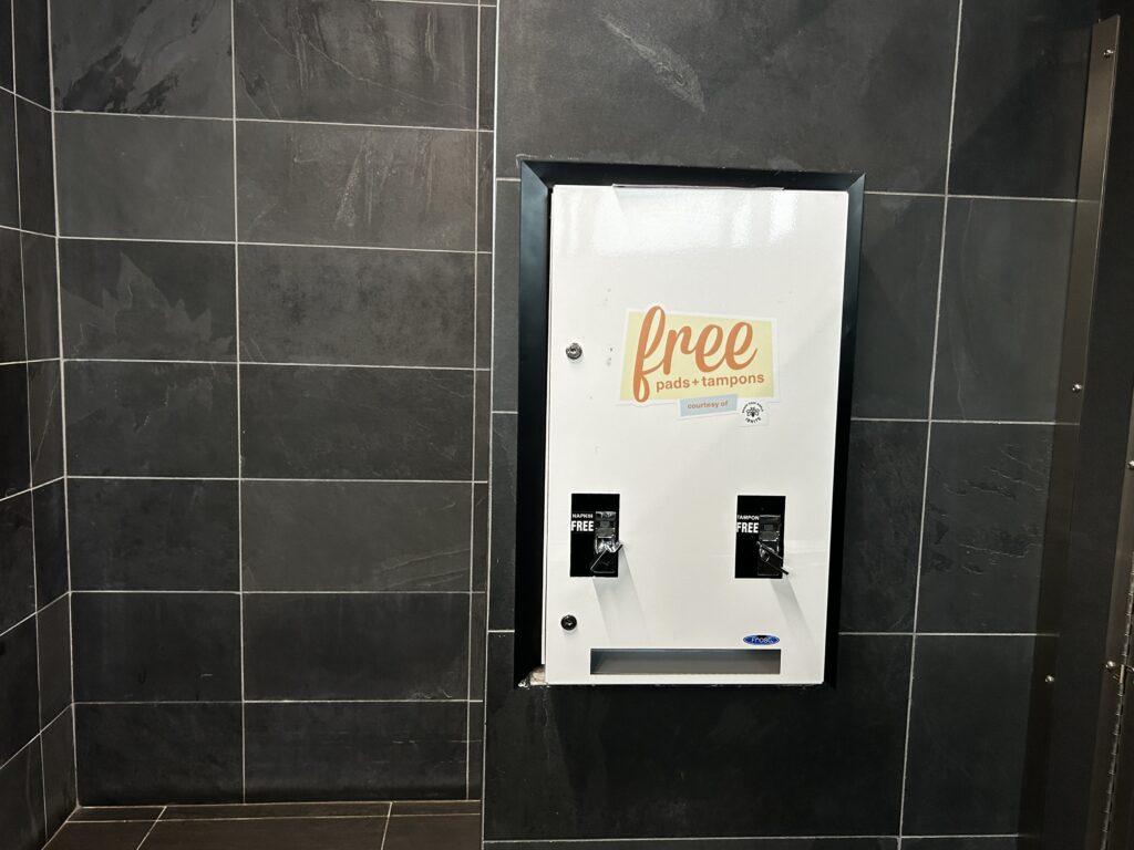 Wall of a women's comfort room at the Humber North Campus, which features a dispensing machine for free pads and tampons.