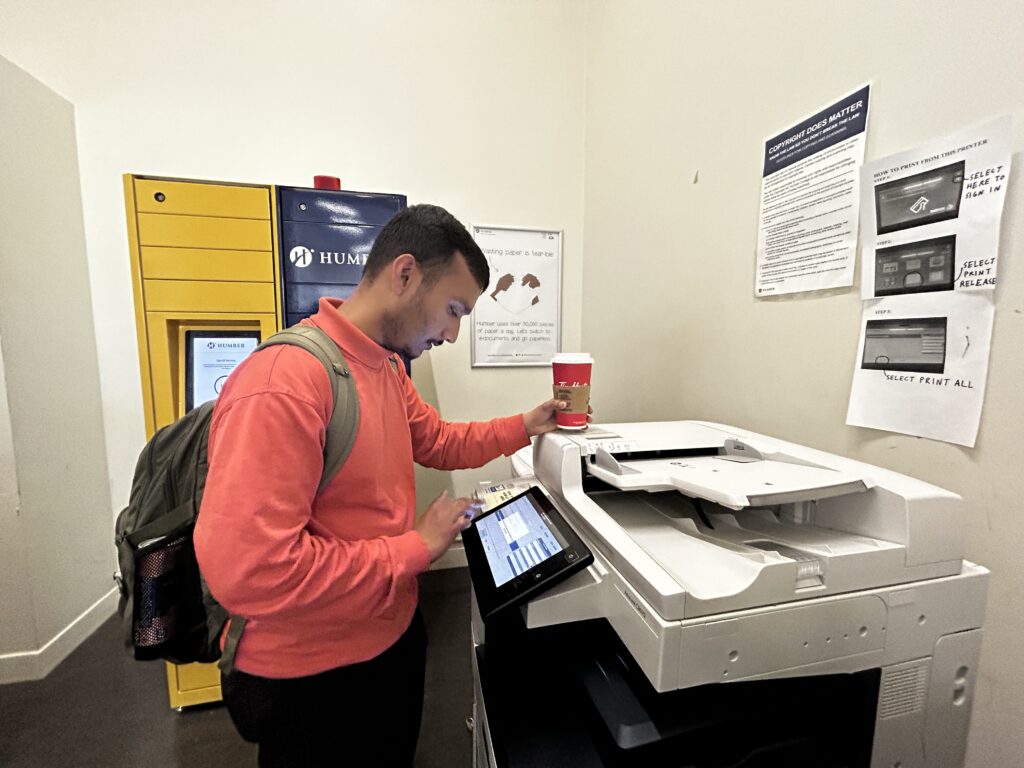 A Humber student inputting his credentials in the printing machine.