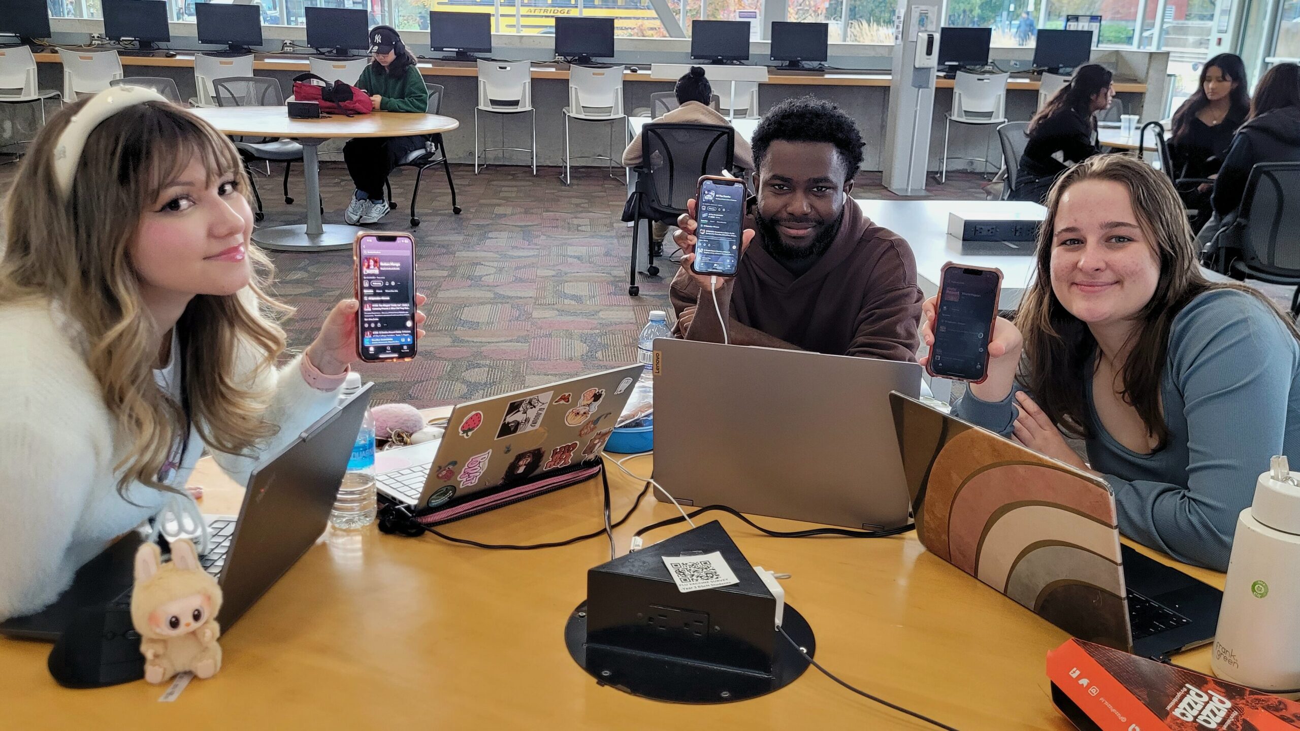 Picture of students Jackson Sparks, Molly Syms-Wilson and another one holding iPhones and showing podcasts they listen to.