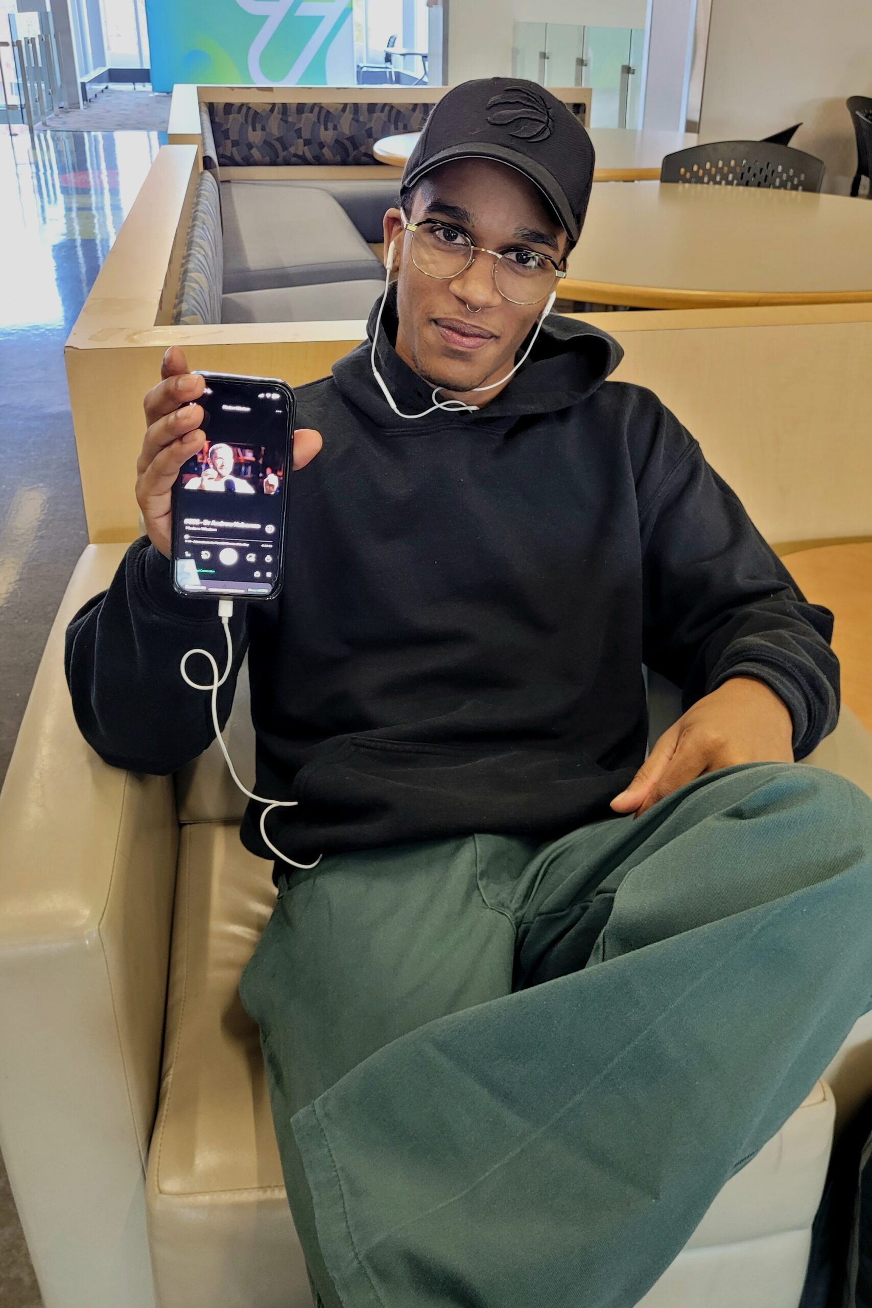 Students Pola Caparas and Julian Smadhin holding iPhones and showing podcasts they listen to.