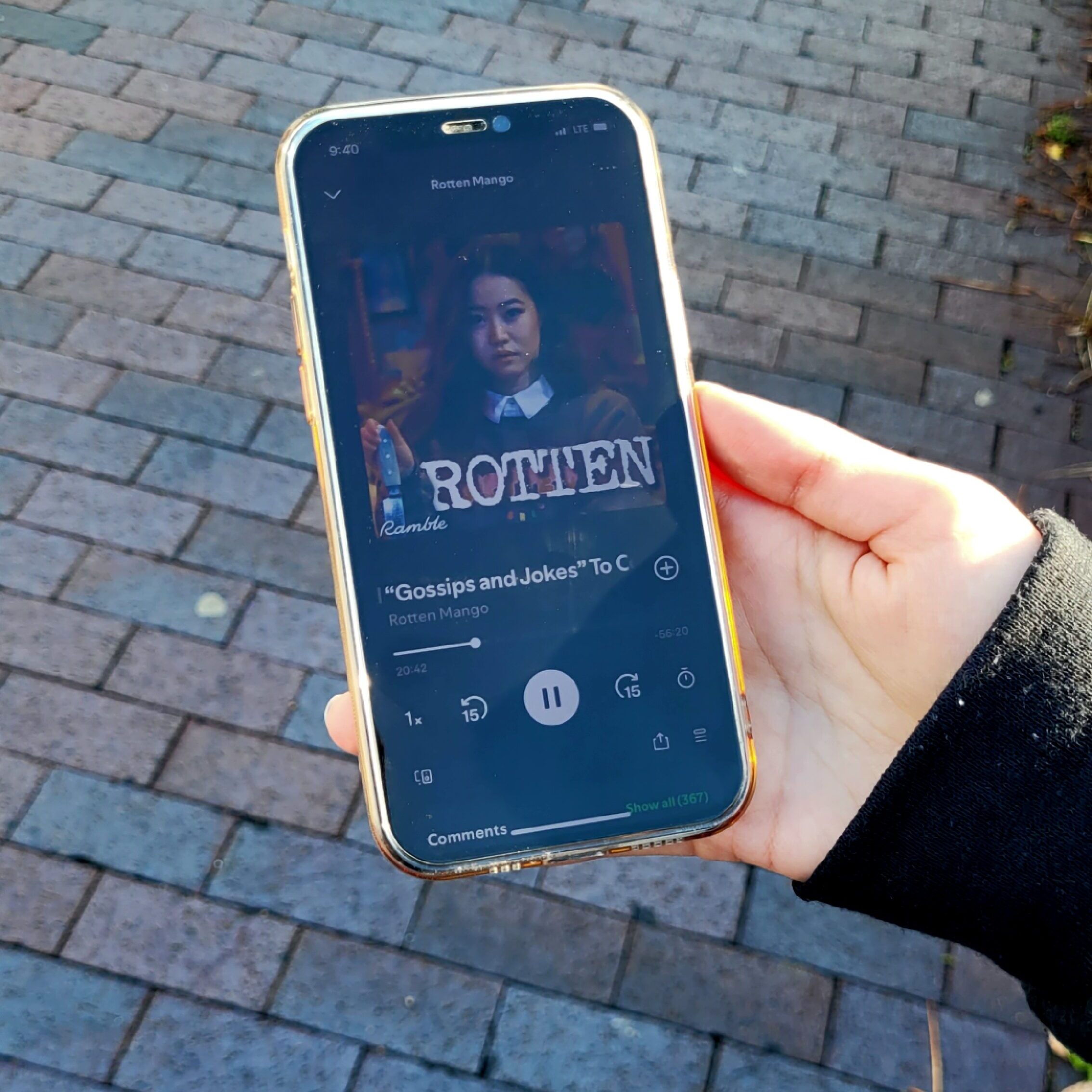 Picture of a person holding an iPhone with a podcast playing.