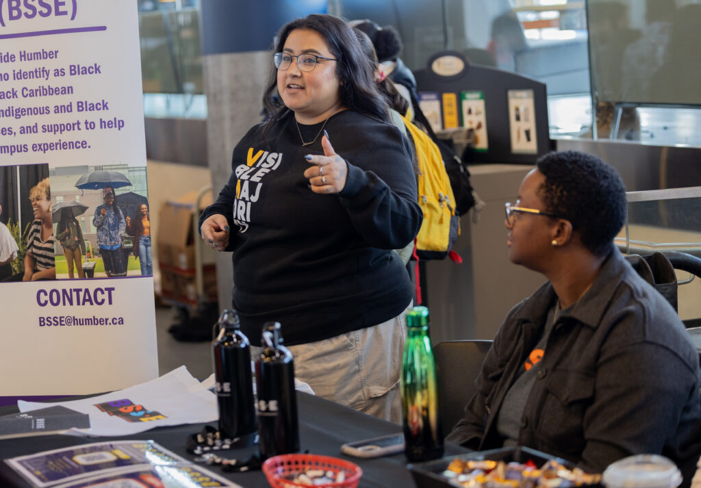 Two people are behind a help desk on campus.