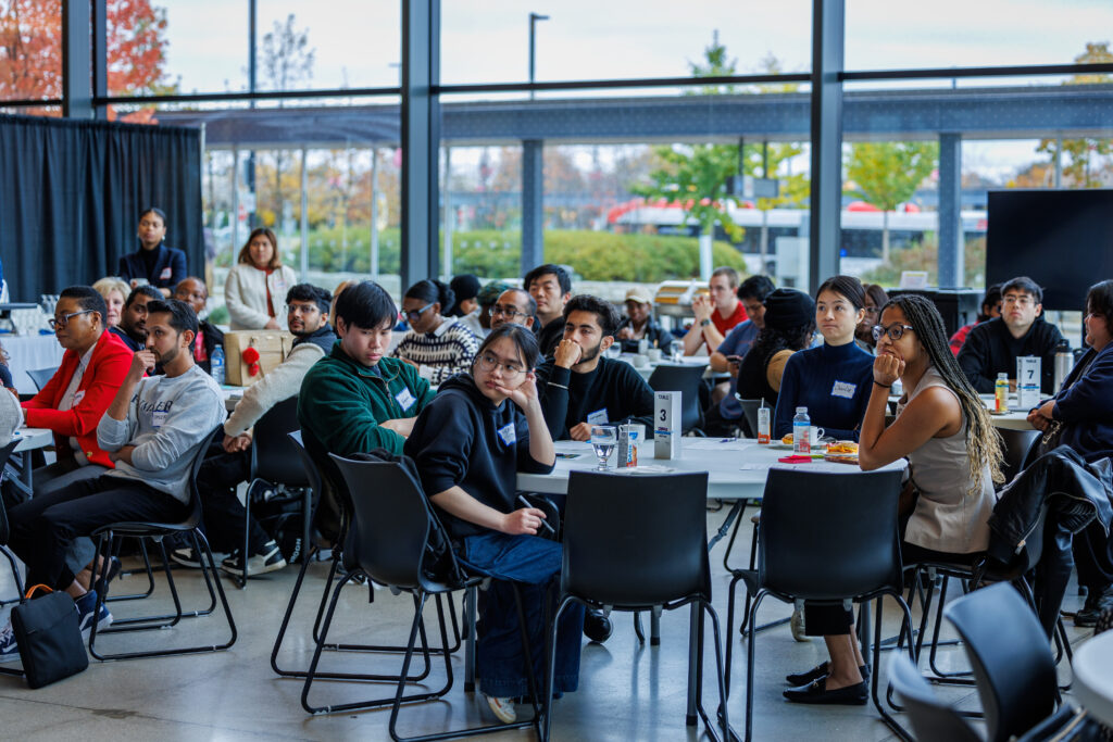 Group of students sitting at different tables during a hackathon.