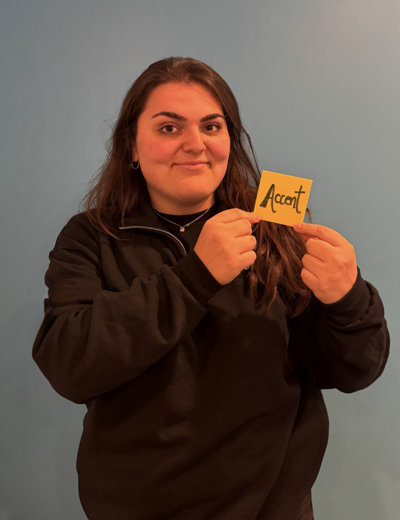 A girl holding a paper with a written word "Accent" that represents one of her talents.