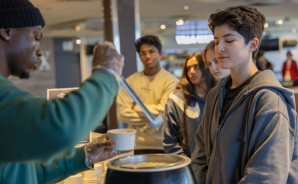 A person serving soup to a student. 