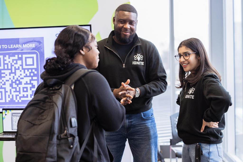 Three people are standing together and having a discussion. 
