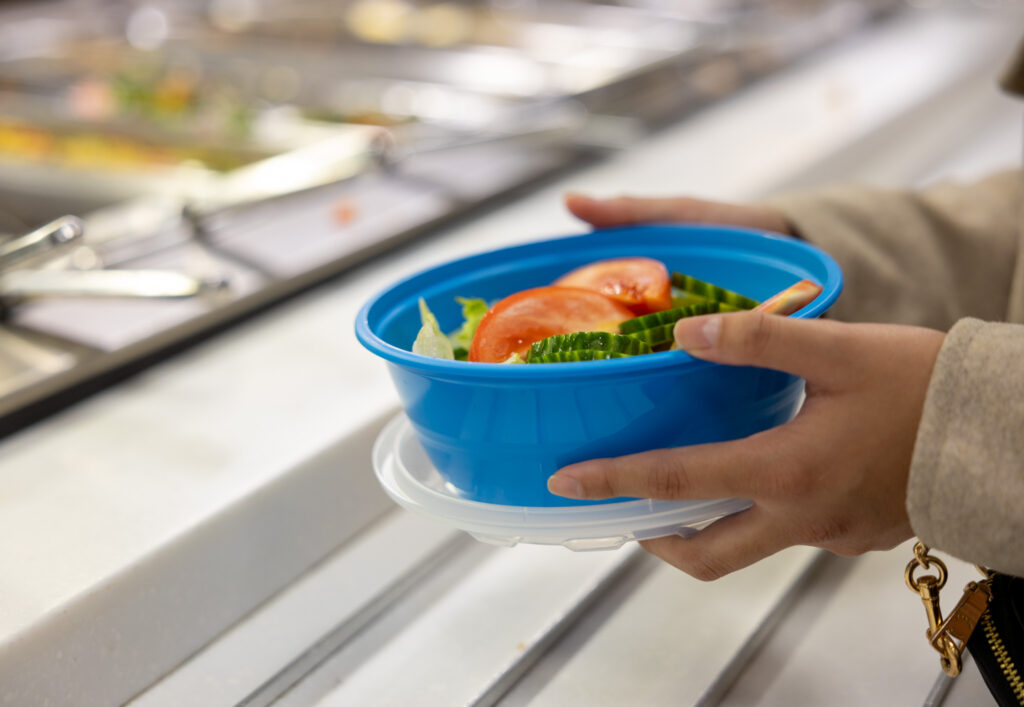 A person getting food with a Friendlier container.