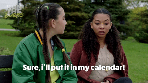 Two women sitting on a park bench and one says, "Sure, I'll put it in my calendar!" to the other 