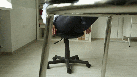 A man relaxing by leaning into an office chair and his legs propped onto a table.