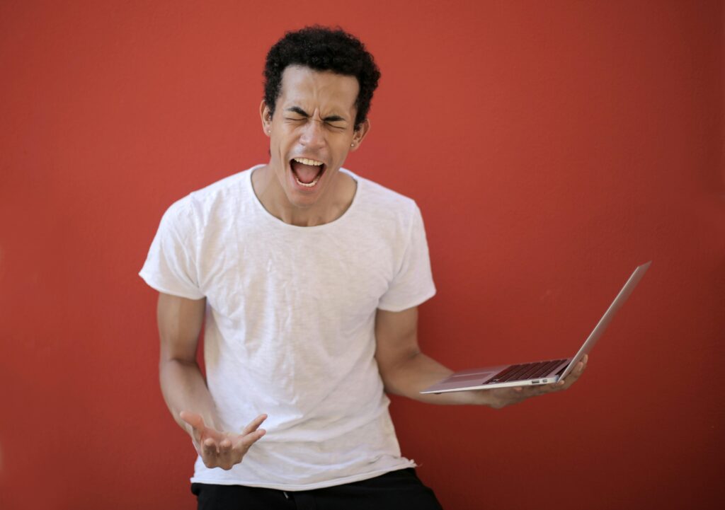 A young male with holding a laptop is screaming.