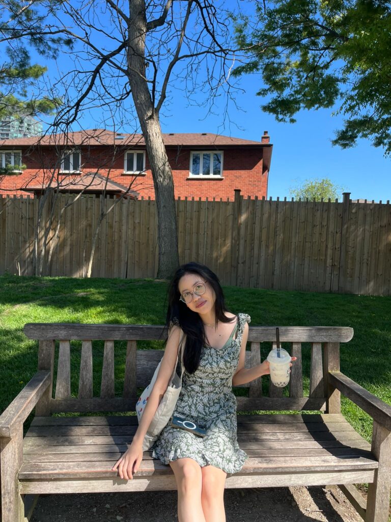 Giovanna Apelabi wearing a green sundress holding a bubble tea and a totebag. street