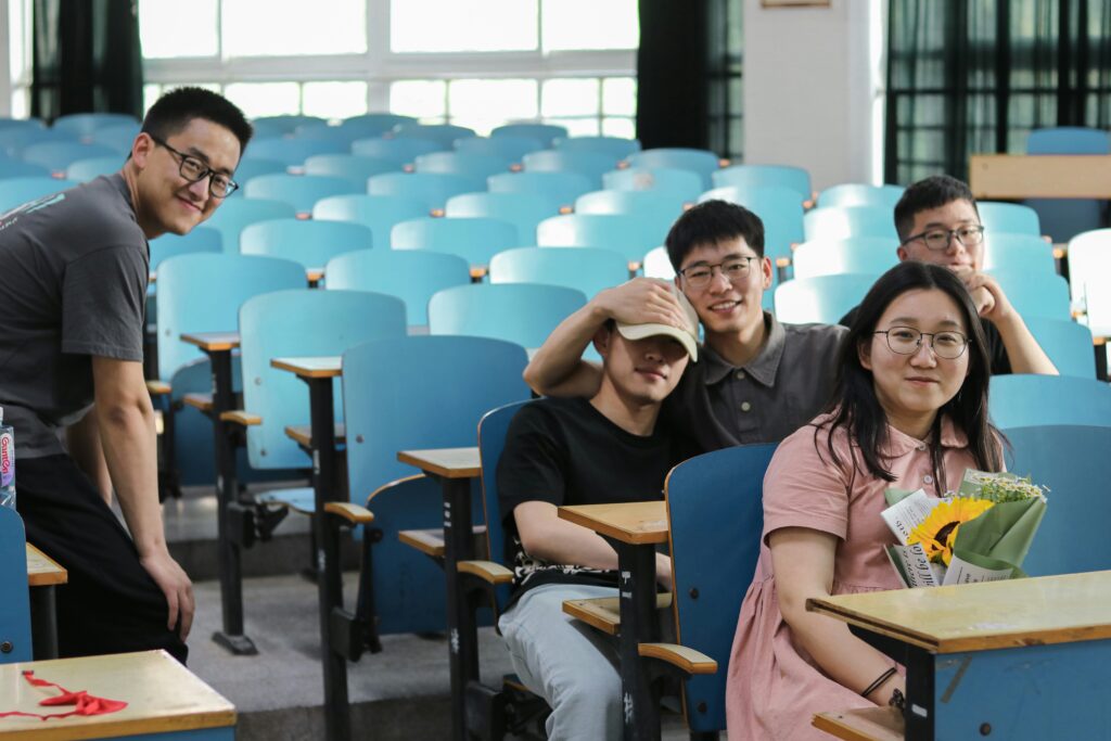 A group of students in a classroom with blue chairs.