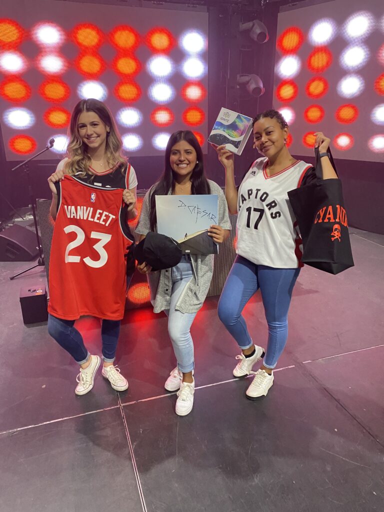 Three women holding Toronto Raptors gifts.