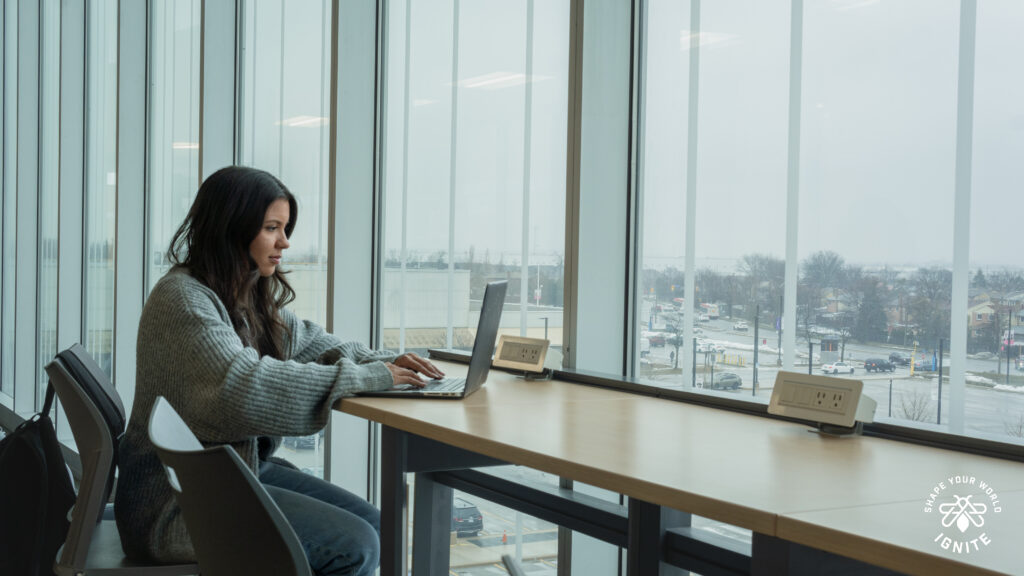 A woman sitting at a desk typing on her laptop.  