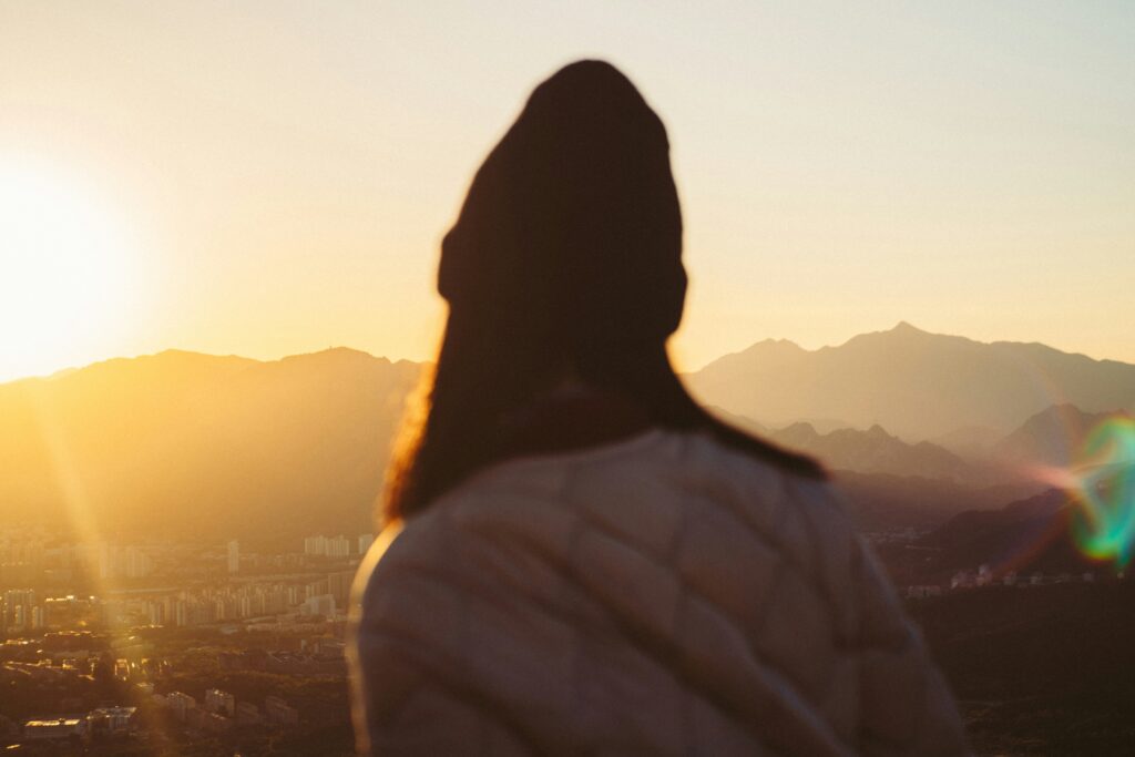 a woman standing on top of a hill overlooking a city