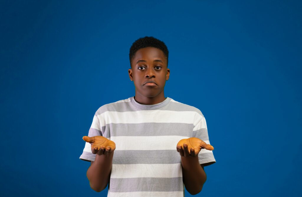 A person holding their hands, palms side up, looking confused toward the camera.