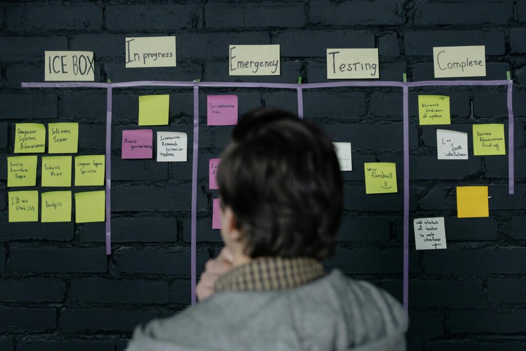 A person staring at a wall full of sticky notes in order of completion.