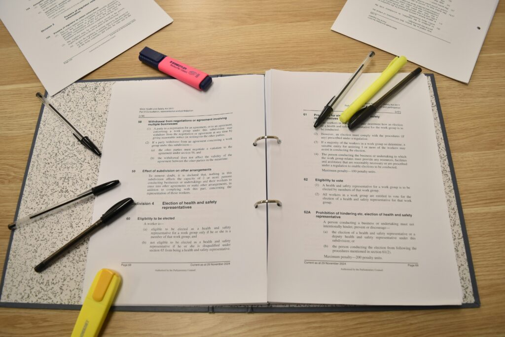 Papers, pens and highlights are laid out on a notebook.