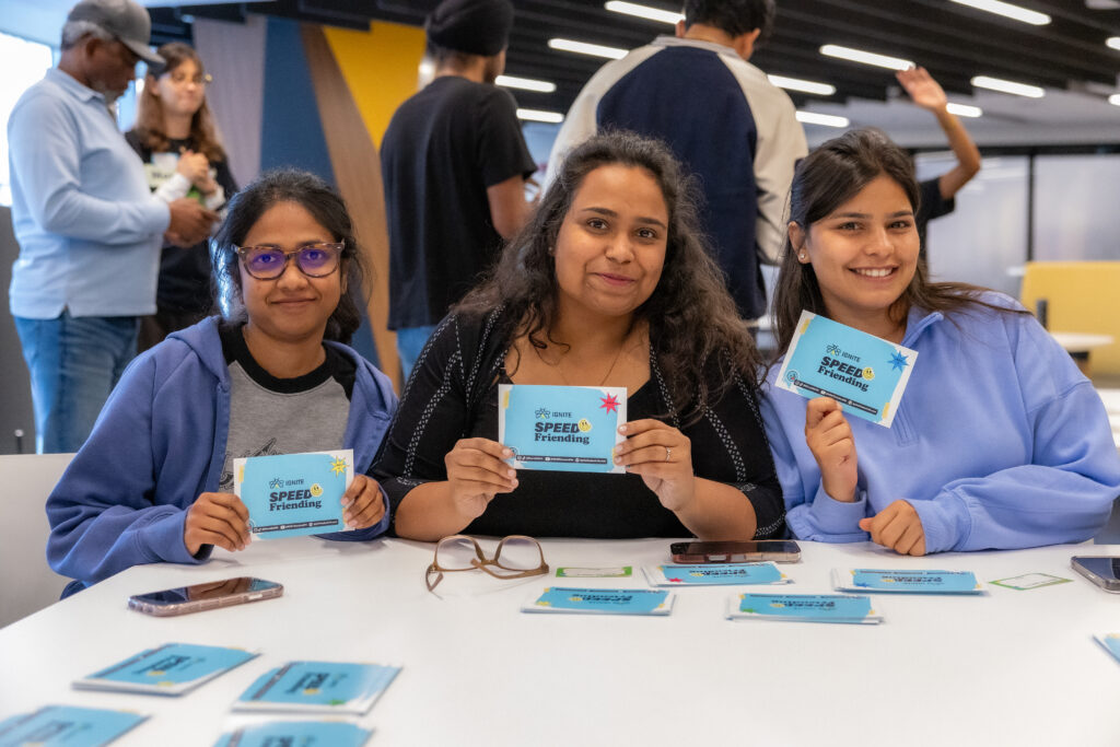A group of students at the IGNITE Speed Friending event holding ice-breaking cards.