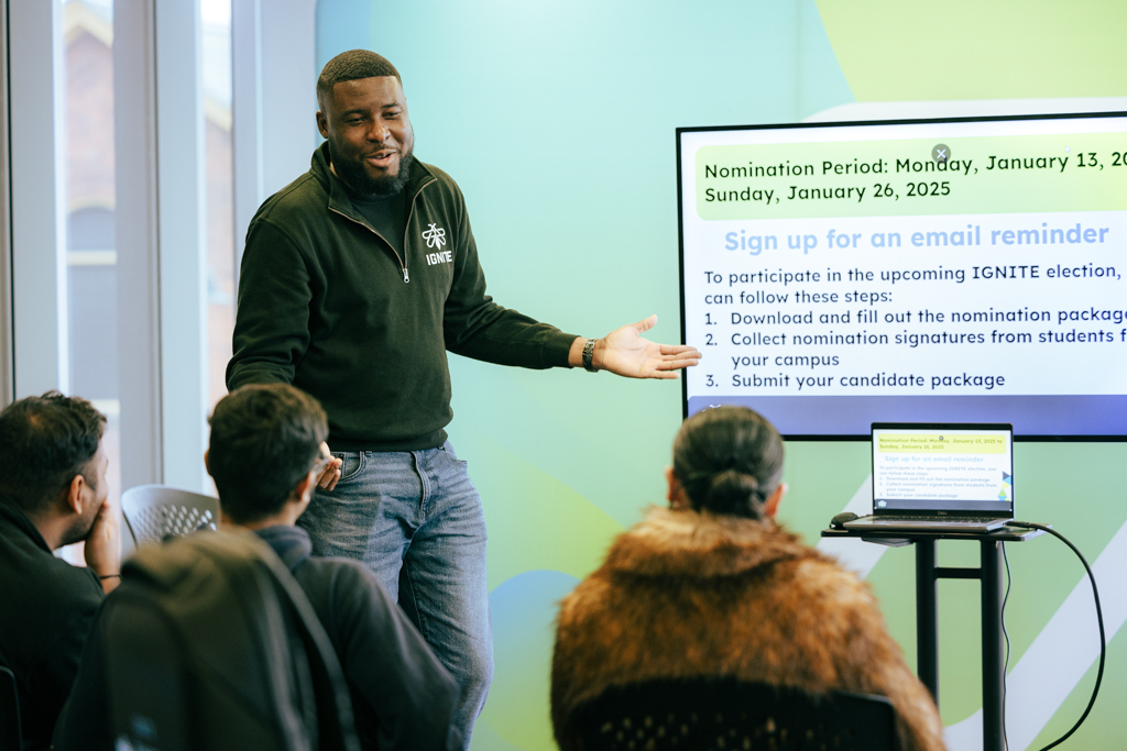 A board of directors member showing students how to sign up for the IGNITE election.