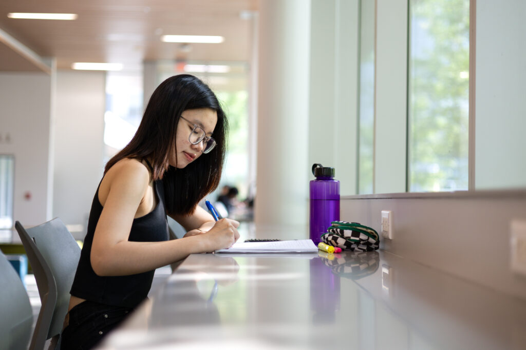a girl with glasses studying on campus
