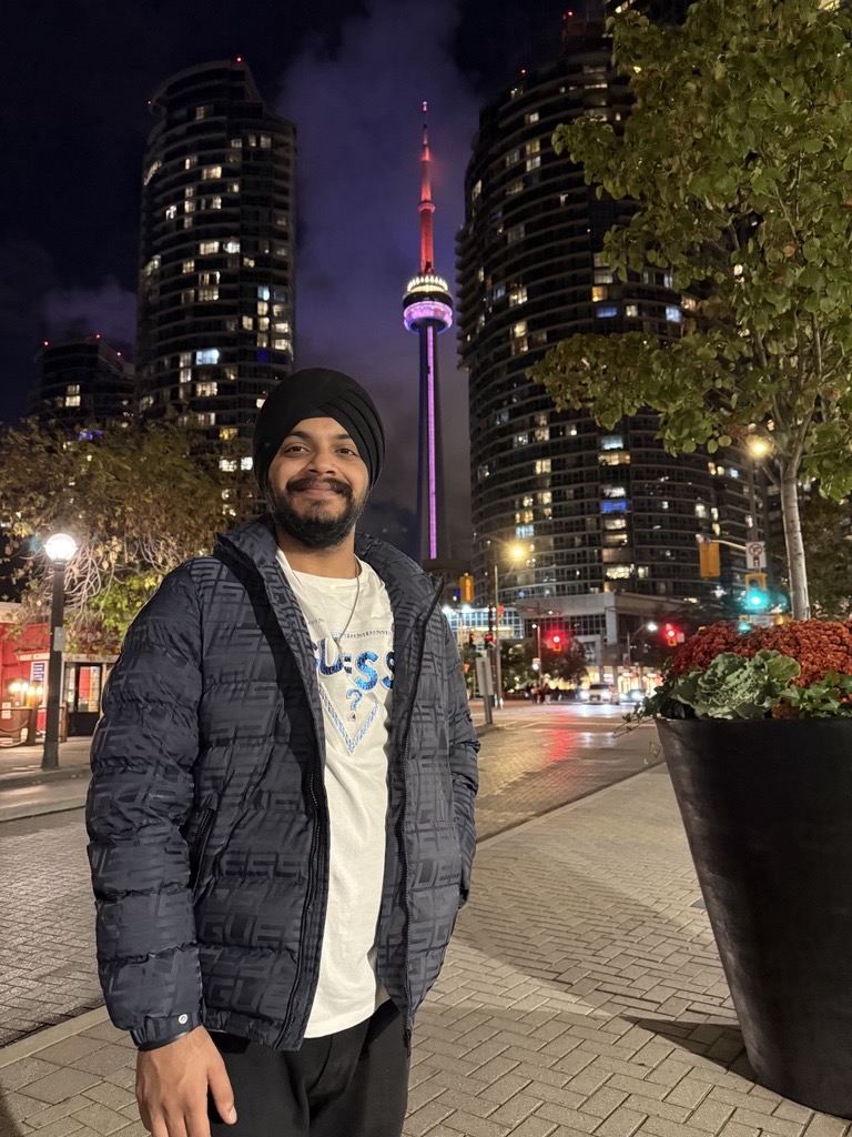 A picture of a man with a winter jacket, and a white and blue shirt underneath with a thin chain necklace.