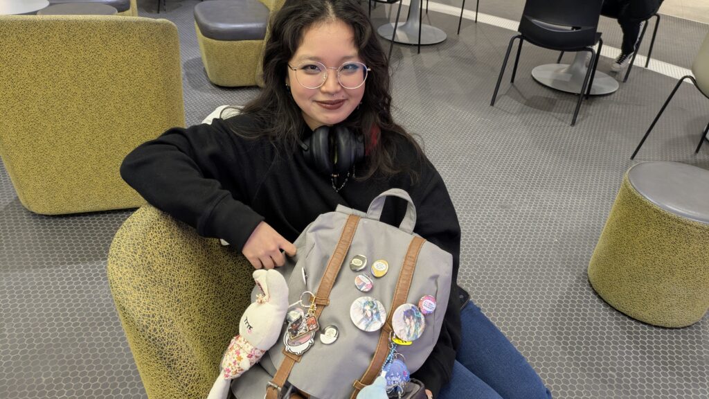 Lilian Nguyen posing with her backpack filled with her express buttons and plushies.