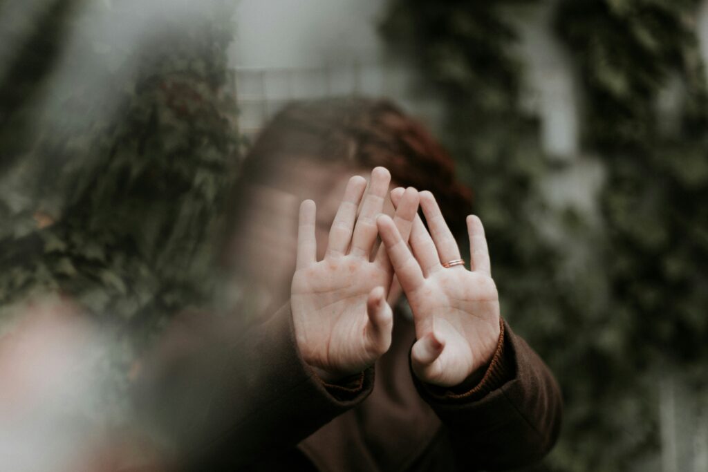 person in brown long sleeve covering their face with the palm of the their hands