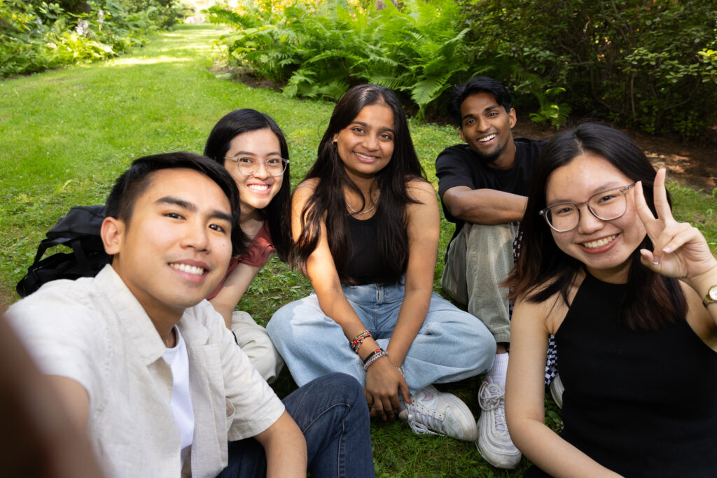 Five students taking a group selfie outdoors.
